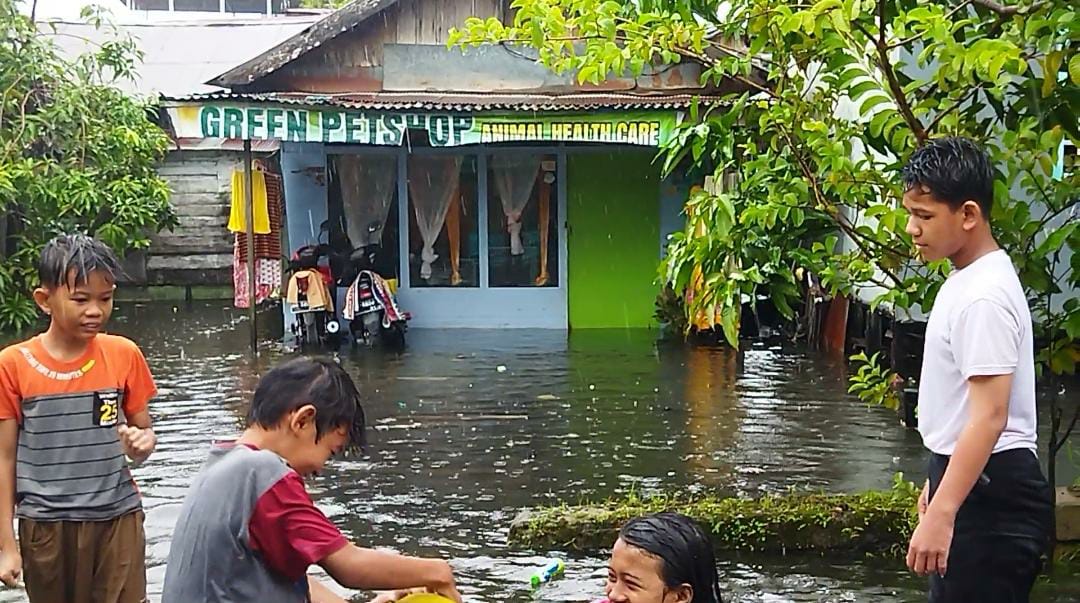 Sejumlah anak-anak terlihat memanfaatkan air banjir di kawasan Prona II