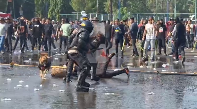 petugas berupaya menahan kerumunan massa yang ricuh pada unjuk rasa