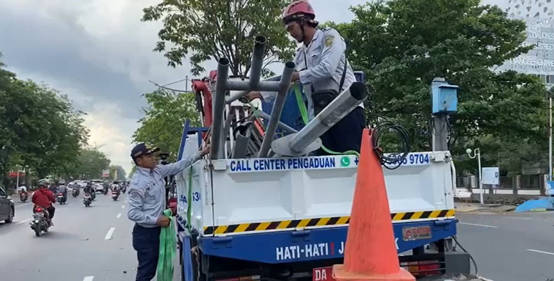 petugas nampak mengangkut tiang penerangan jalan umum yang roboh